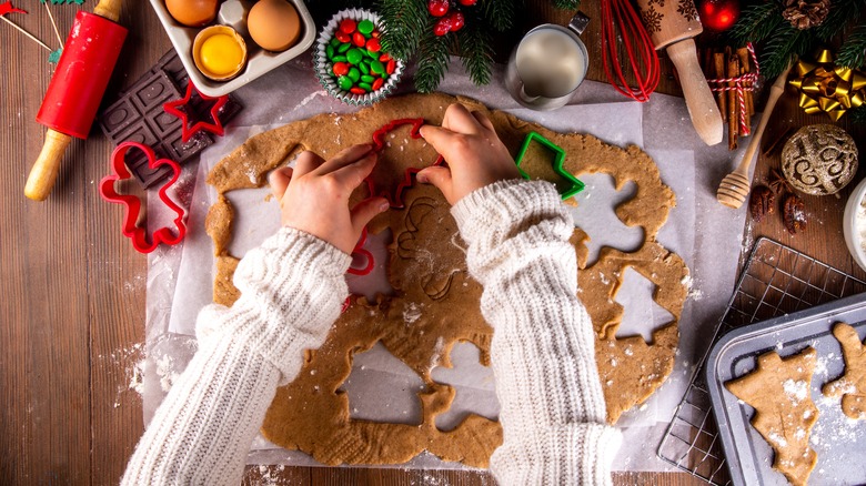 overhead shot of child's hands cutting out gingerbread cookies