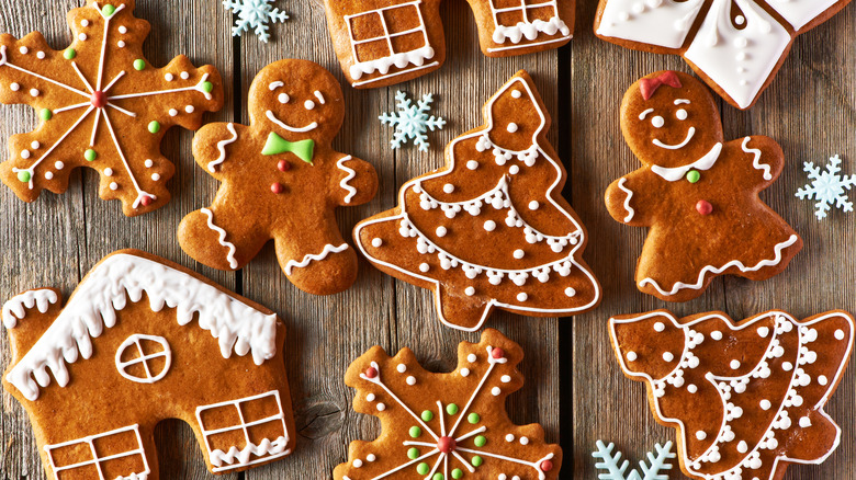 Several decorated gingerbread cookies in various shapes lay flat on wooden table.