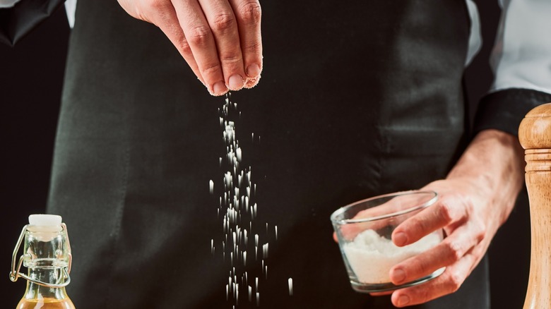 Close up chef salting dish