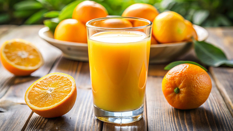Orange juice surrounded by oranges.