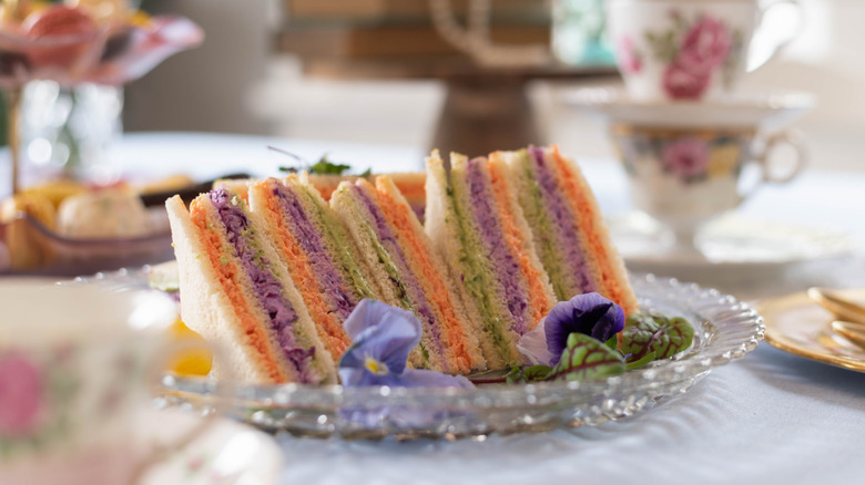 Triangular cut colorful ribbon sandwiches on a plate.