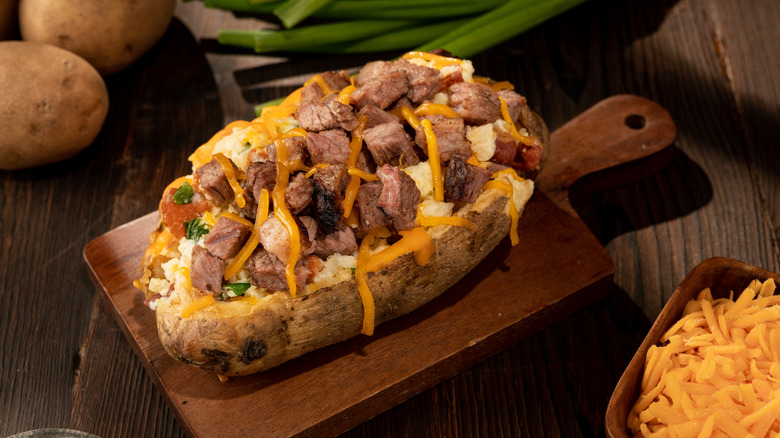 a loaded baked potato is piled high with brisket and cheese.