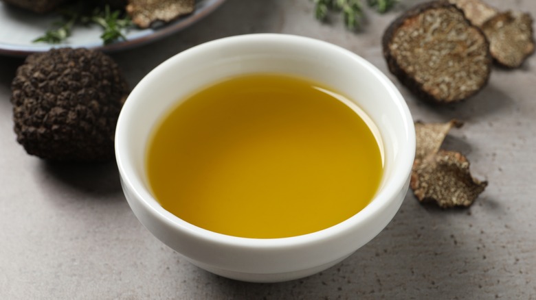 bowl of oil surrounded by truffles
