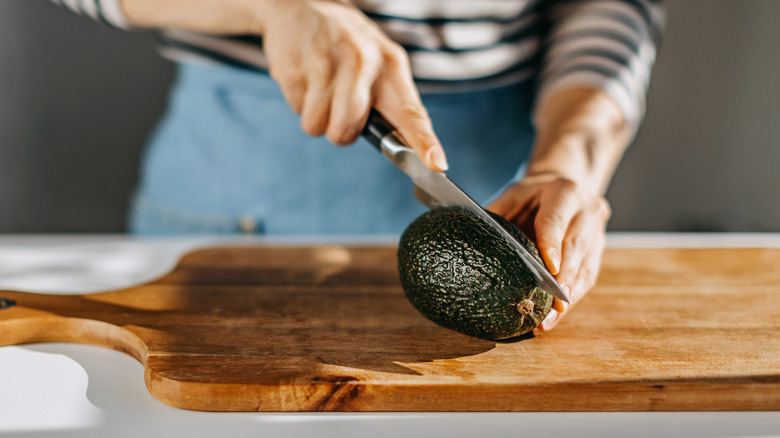 person cutting avocado with knife