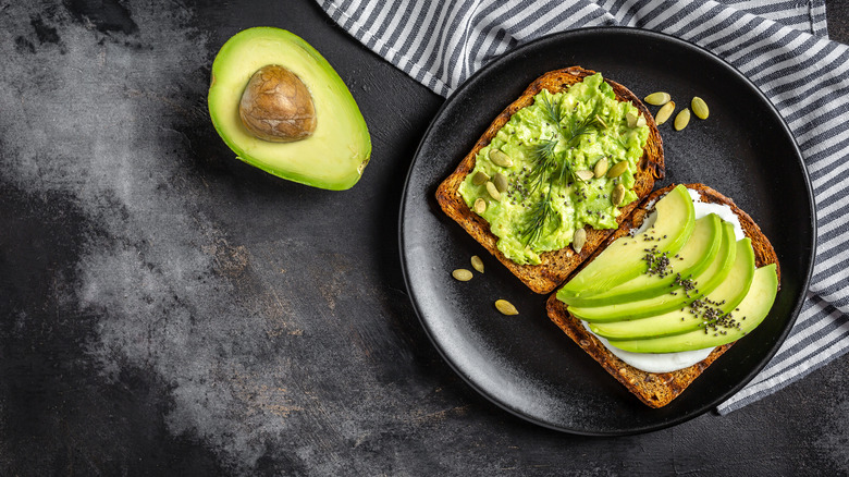 sliced open avocado next to slices of avocado toast