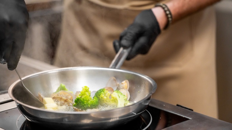 pro cook makes food with saute pan on stovetop