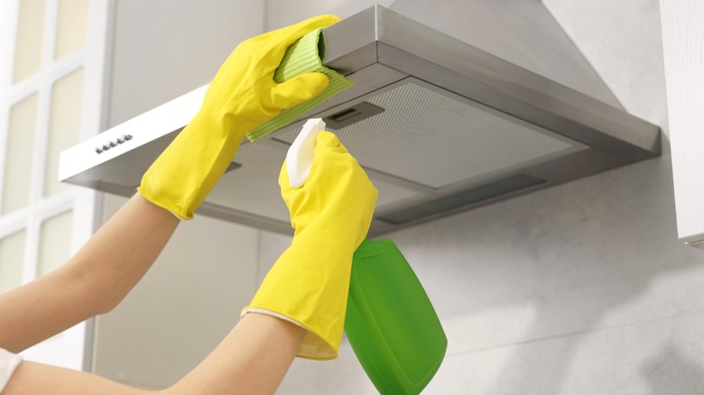 Person cleaning hood vents in home kitchen