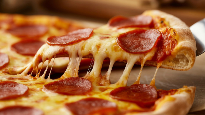 A slice of pepperoni pizza being lifted up