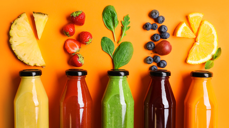 organic juices in glass bottles with fresh fruit above