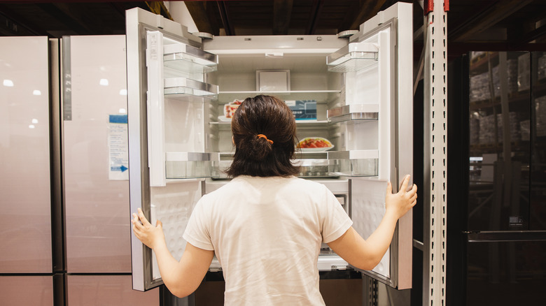 A woman looking inside of a display refrigerator at a store