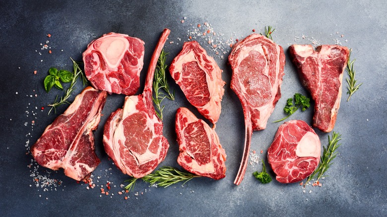 different steaks against black background with herbs
