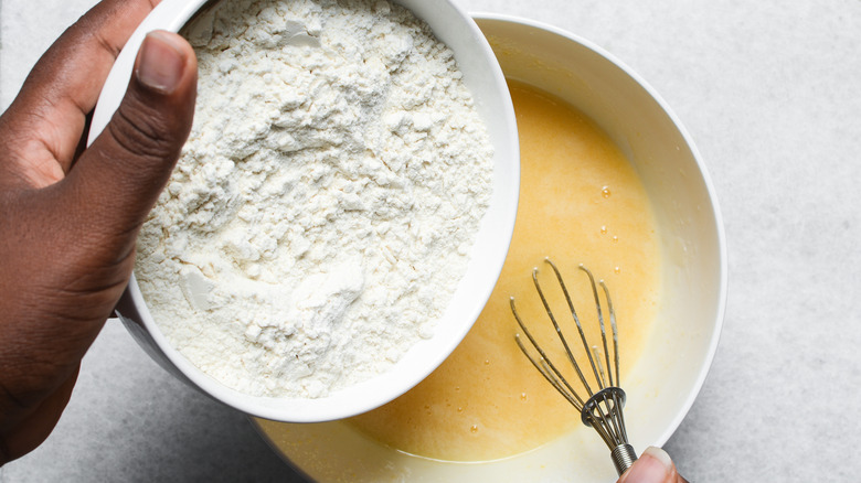 A close-up overhead shot of someone mixing flour into cake batter,