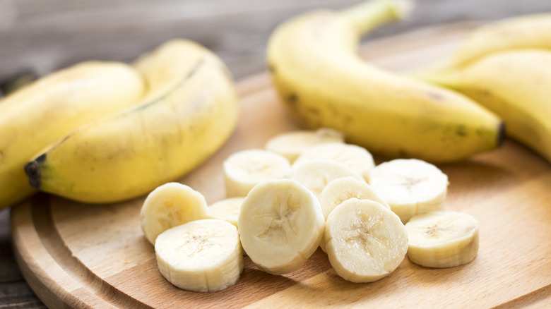 bananas and banana slices on a wooden cutting board