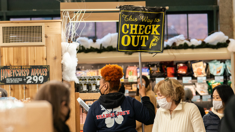 person holding check out sign at trader joe's 
