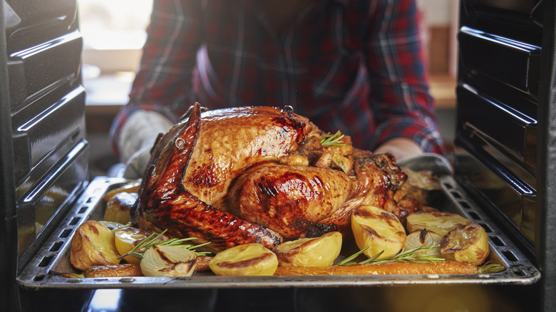 person taking turkey out of oven