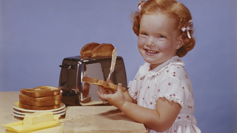 a little girl butters toast in vintage photo