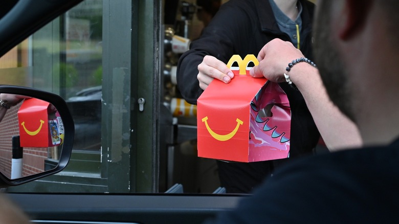 mcdonald's worker hands a happy meal to a driver