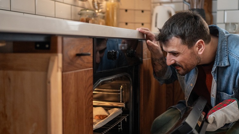 man checks open kitchen oven