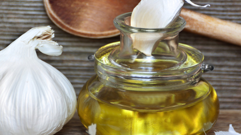 Close-up of a garlic clove and a jar of oil