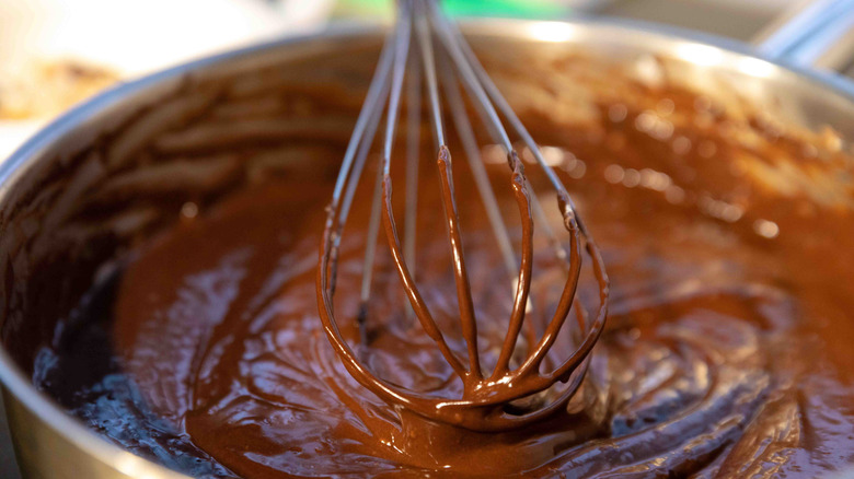 A close-up of brownie batter being stirred with a whisk