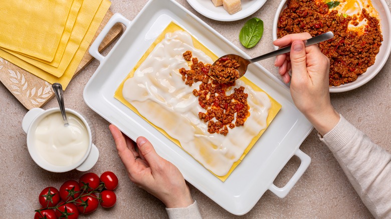 layering lasagna with bechamel and bolognese sauce