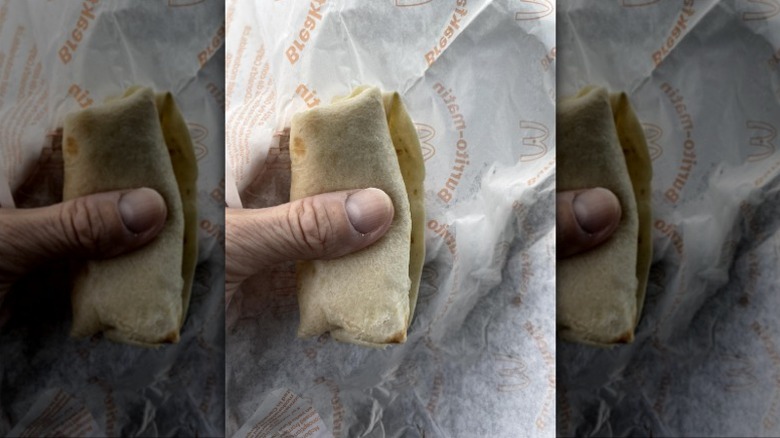 Hand holding incredibly small McDonald's breakfast burrito.