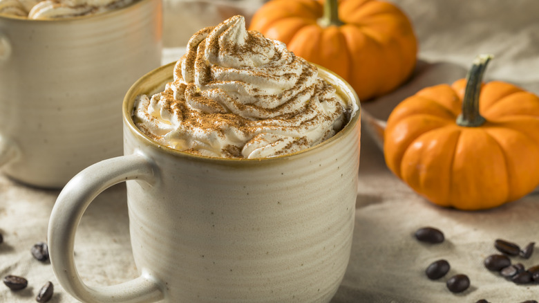 White mug of coffee with cream and pumpkin spice.