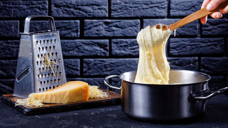 mixing melted cheese in a pot with a wooden spoon