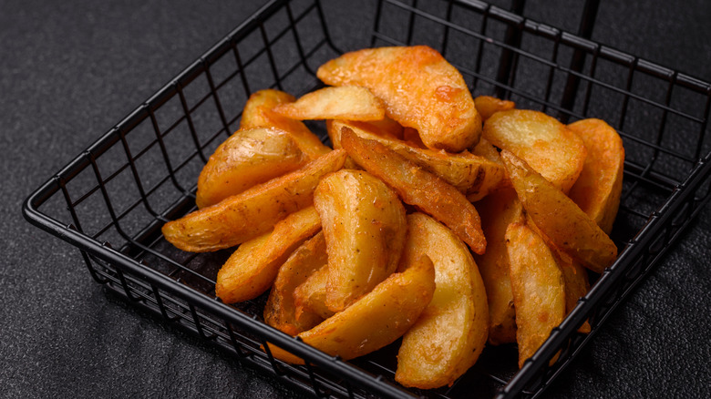 Fried potato wedges in fryer basket