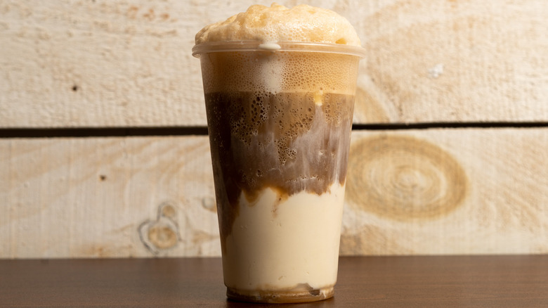 Root beer float in plastic cup.