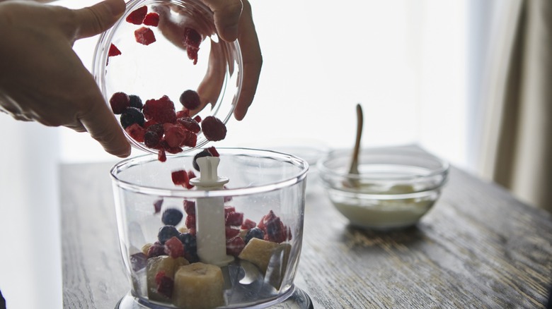 hands put fruit in a food processor