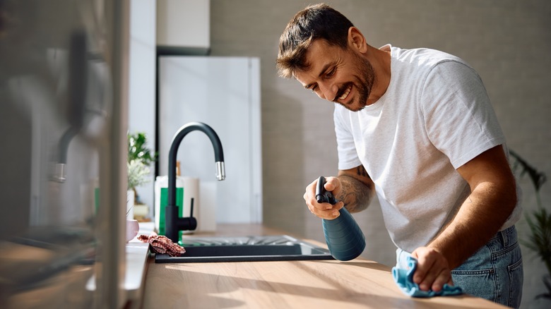 Someone cleaning his kitchen counters next to a sink
