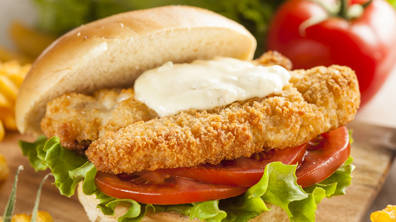 A breaded fish sandwhich topped with tartar sauce