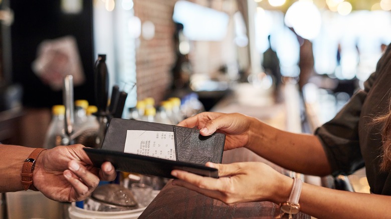 hands pass billfold at a restaurant