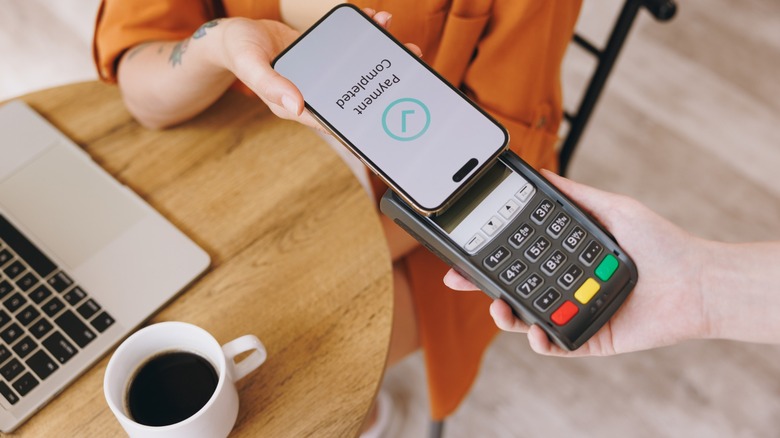 a person pays a bill at a cafe with their phone