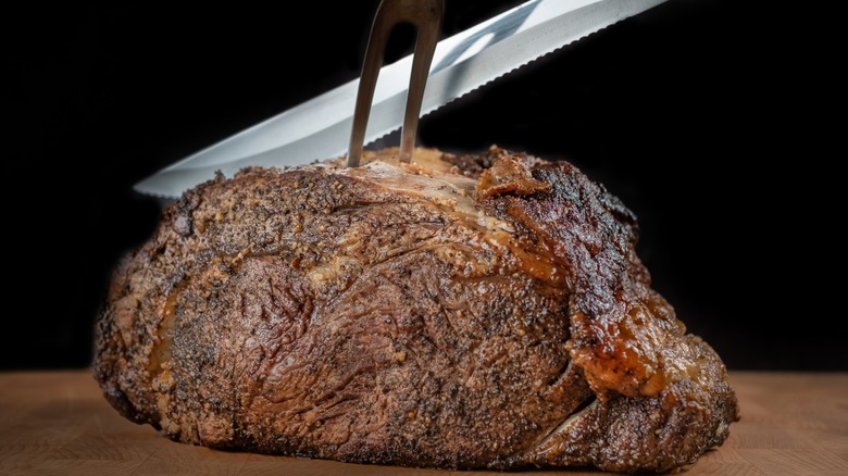 prime rib being sliced with knife and fork