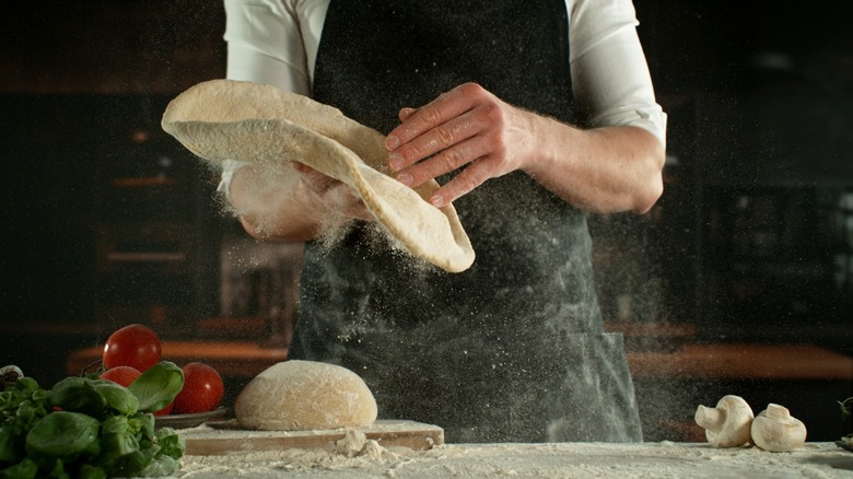 Person tossing pizza dough from hand to hand.