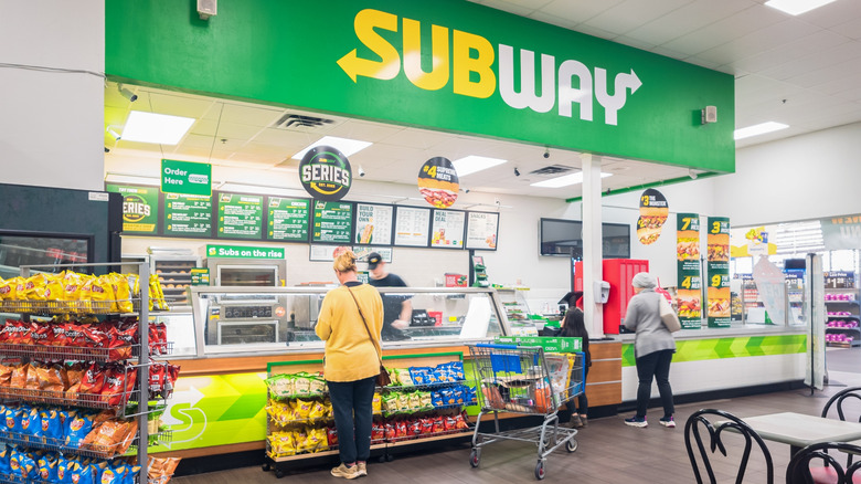 Customers at counter inside a Subway restaurant.