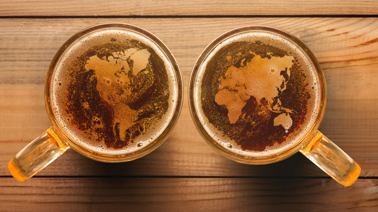 top-down view of two mugs of beer with world map pictured in their foam