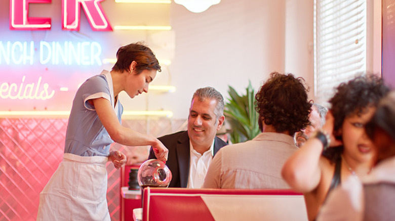 Server pouring coffee for customer in diner