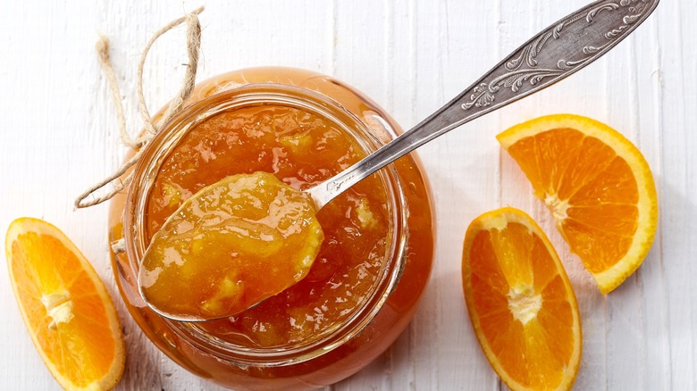 orange marmalade in glass jar with spoon