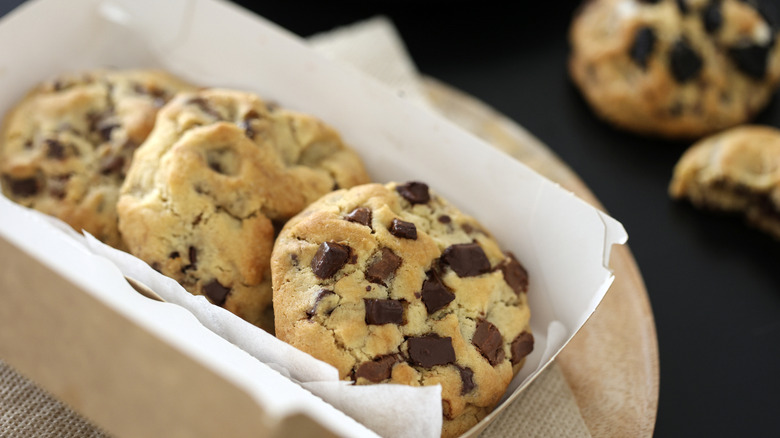 A close-up of a small paper box of three chocolate chip cookies