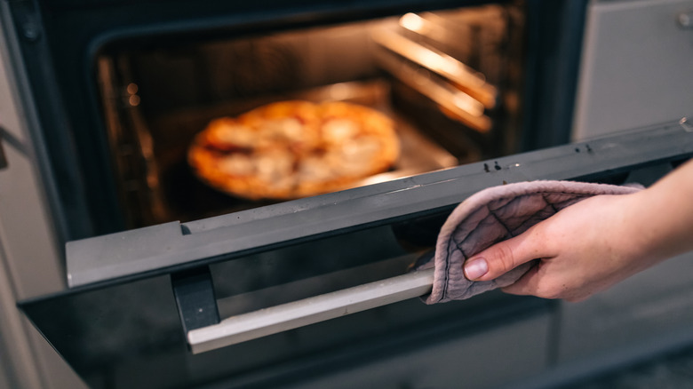 A person looks at a frozen pizza in the oven