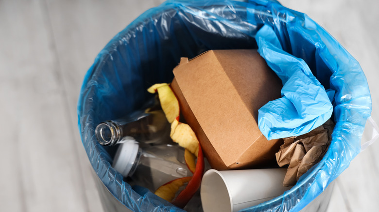 closeup of trash in a kitchen trash can with a blue trash bag liner