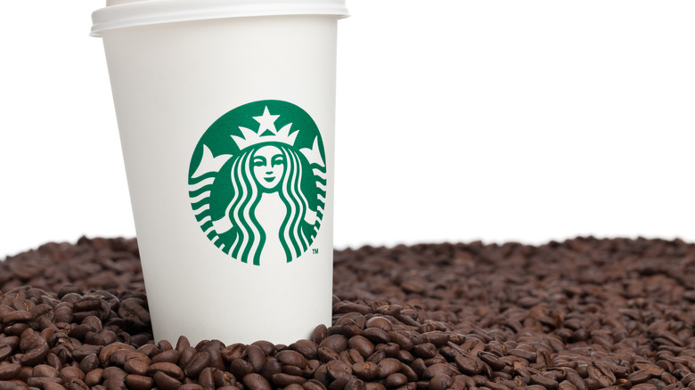 Starbucks coffee cup surrounded by coffee beans