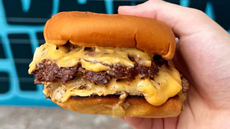 Closeup of person holding cheeseburger.