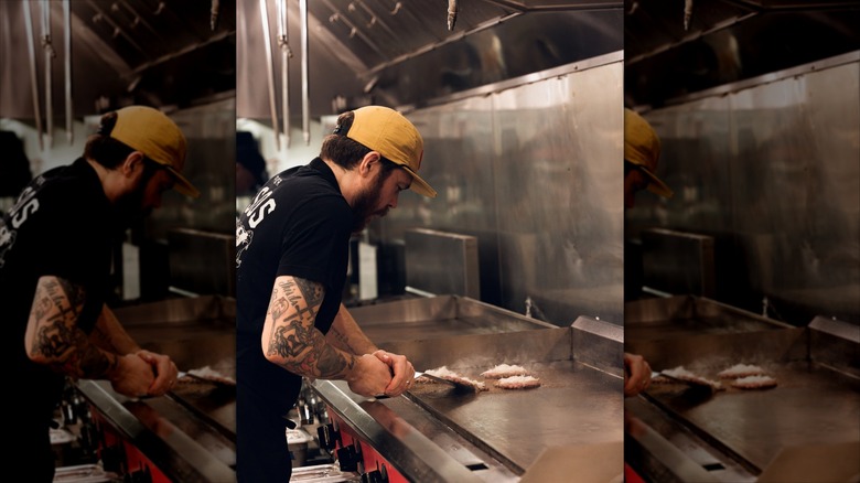 A shot of NADC Burger founder Phillip Frankland Lee making their signature burgers at a grill
