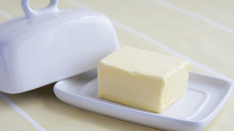 A chunk of butter sits on a white dish
