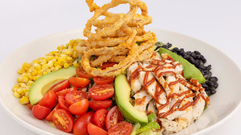 Salad with chicken, barbecue sauce, onion rings, tomatoes, and avocado