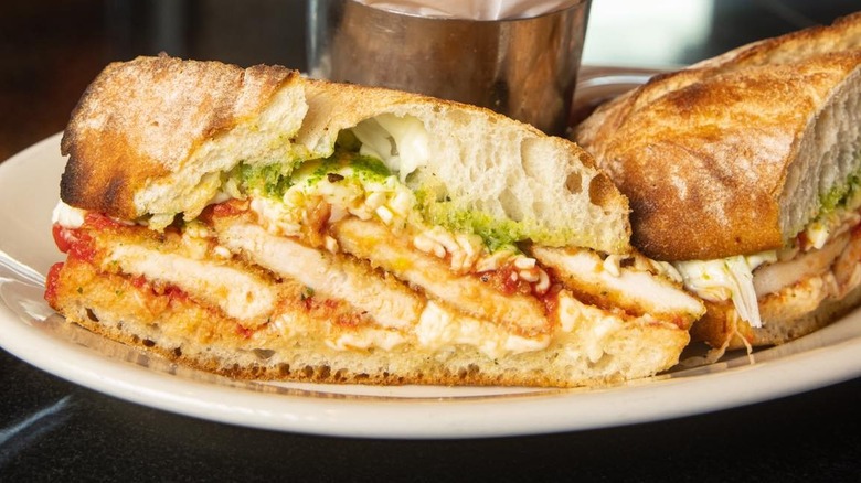 Chicken Parmesan sandwich cut in half on plate with fries